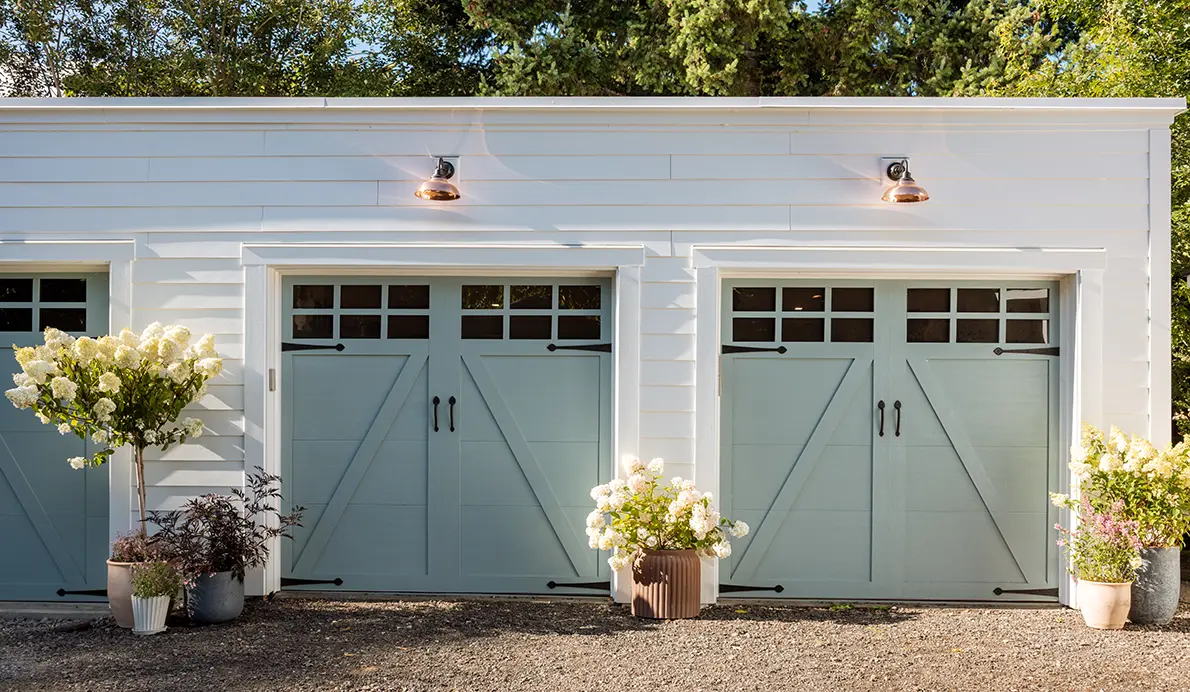 White garage with blue doors and flowers.
